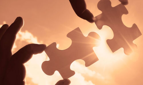 fingers holding puzzle pieces up to the light