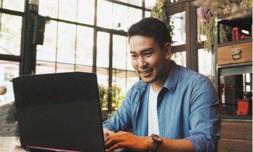Asian game developer working at his laptop