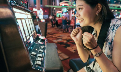 Woman excitedly playing at a casino slot machine